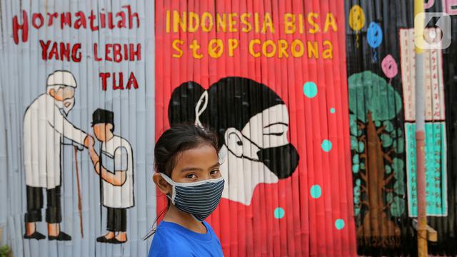 Seorang anak kenakan masker dengan latar belakang mural Indonesia Bisa Stop Corona di Lapangan Bulutangkis, Kampung Kali Pasir, Jakarta(Liputan6.com/Feri Pradolo)