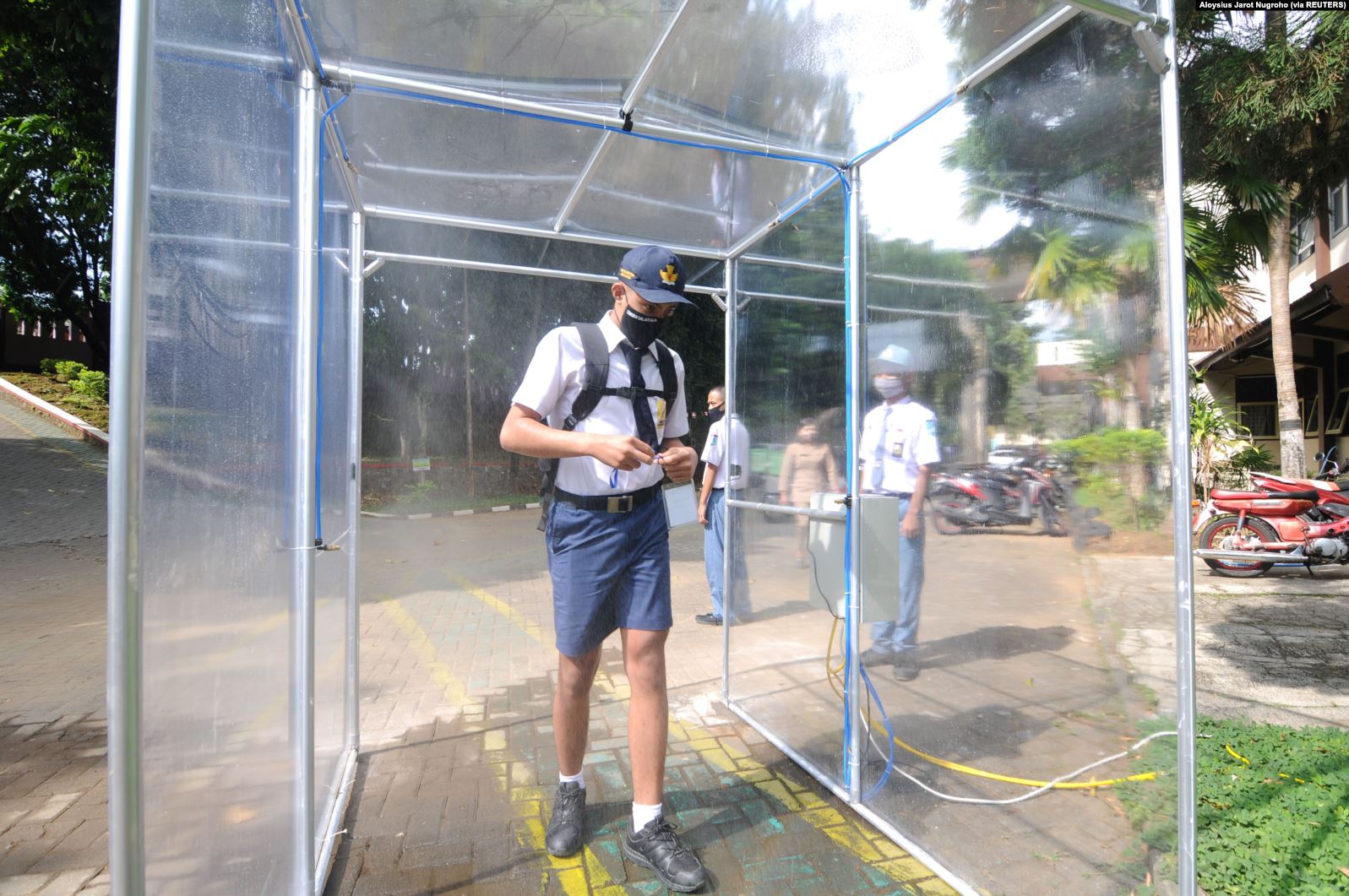 Seorang siswa yang memakai masker pelindung mask ke dalam ruang desinfeksi setelah pemerintah Indonesia membuka kembali sekolah dengan menerapkan proses pembelajaran tatap muka di tengah wabah Covid-19 di Salatiga, Provinsi Jawa Tengah, 13 Juli 2020/Reuters