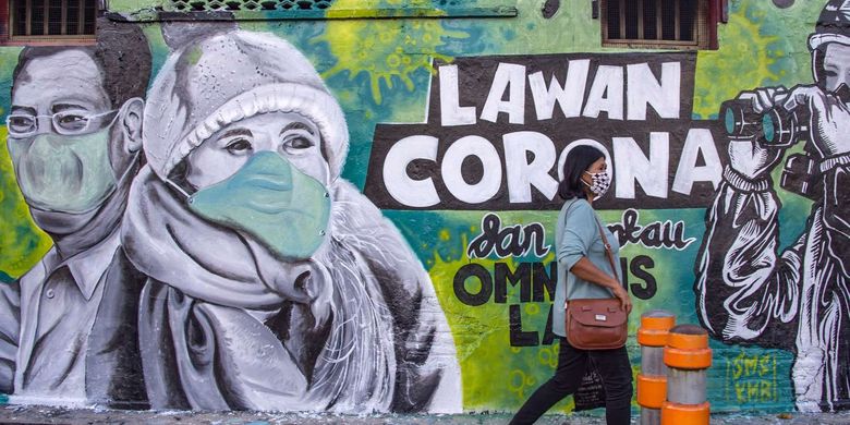 ilustrasi/warga berjalan di depan mural lawan corona